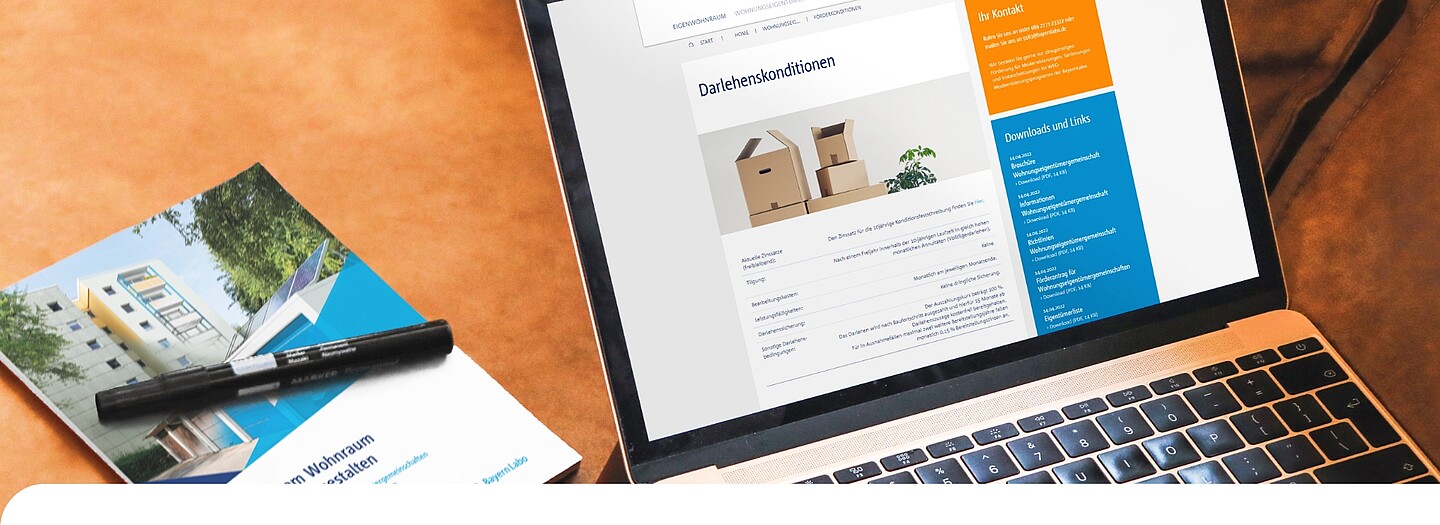 WEG-Broschüre und -Website auf Laptop: Darlehenskonditionen für Wohnungseigentümergemeinschaften